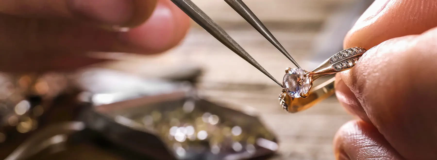 A close-up view of someone's hands carefully inspecting and adjusting a golden engagement ring with a diamond center stone