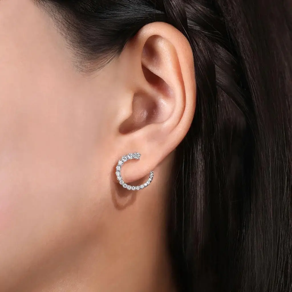 Close-up of a person's ear showing two diamond hoop earrings