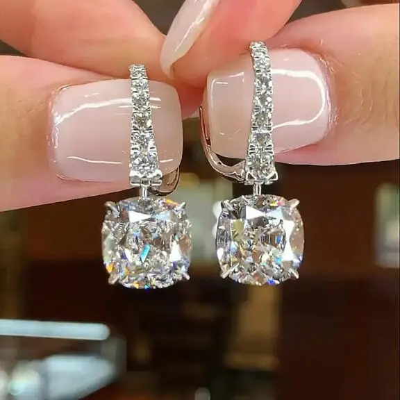 Close-up of a person's hand wearing diamond stud earrings