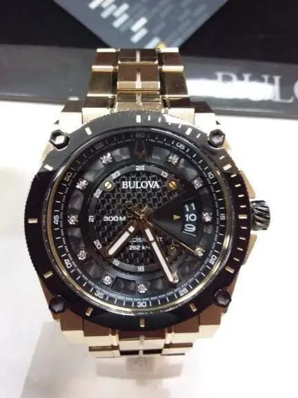 A close-up view of a gold and black Bulova watch with a carbon fiber style face