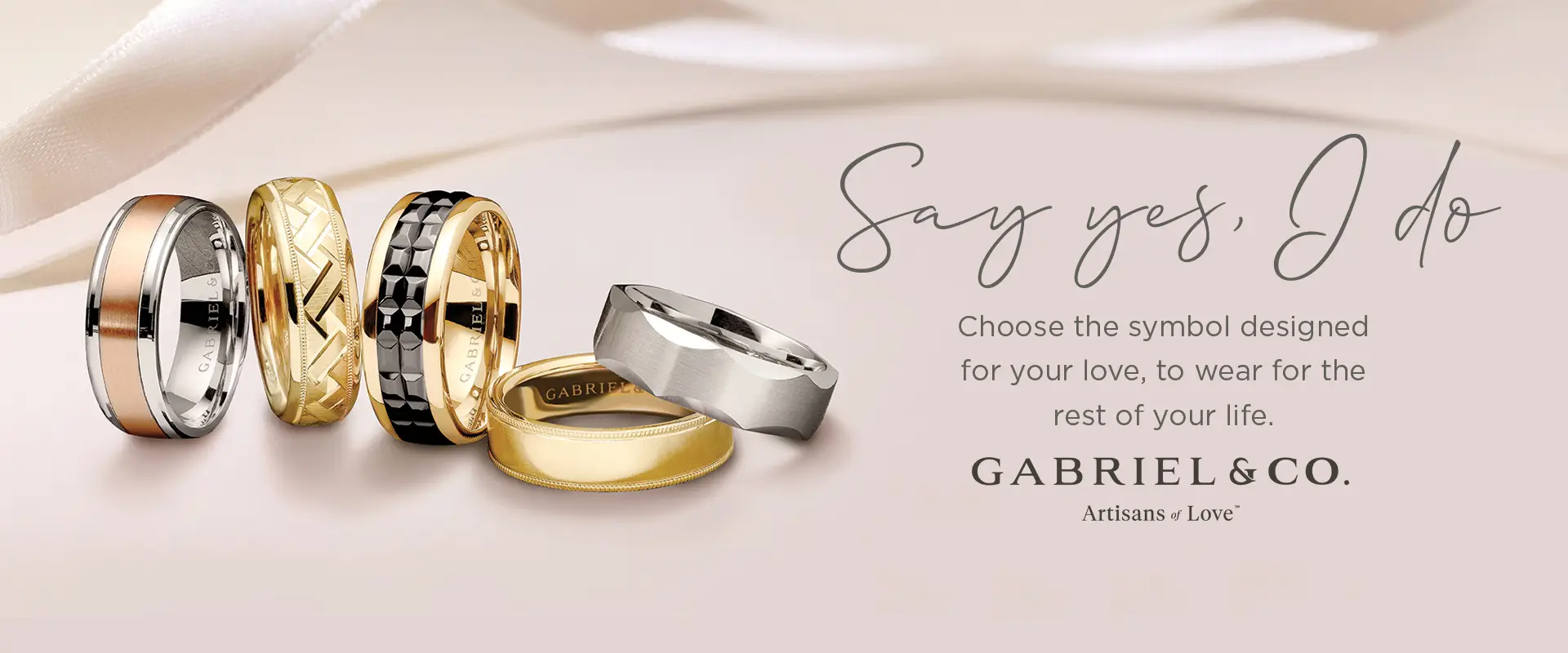 A collection of gold and silver rings with intricate designs, along with the text 'Say yes, I do. Choose the symbol designed for your love, to wear for the rest of your life. GABRIEL & CO. Artisans of Love'.